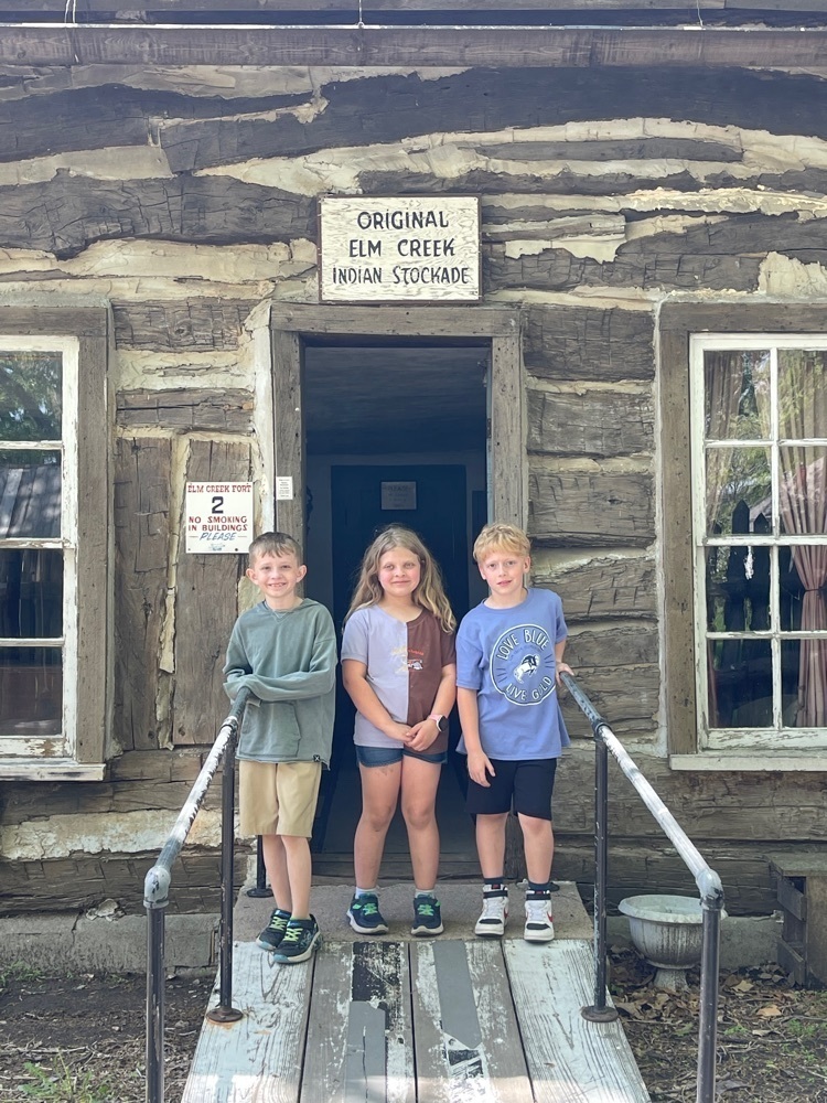 kids at a log cabin