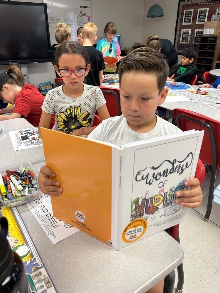 Elementary students reading a book they got published about wildlife.