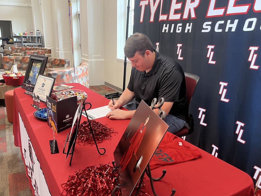 Brenden Mitchell signing his letter of commitment to lift at Blue Mountain College