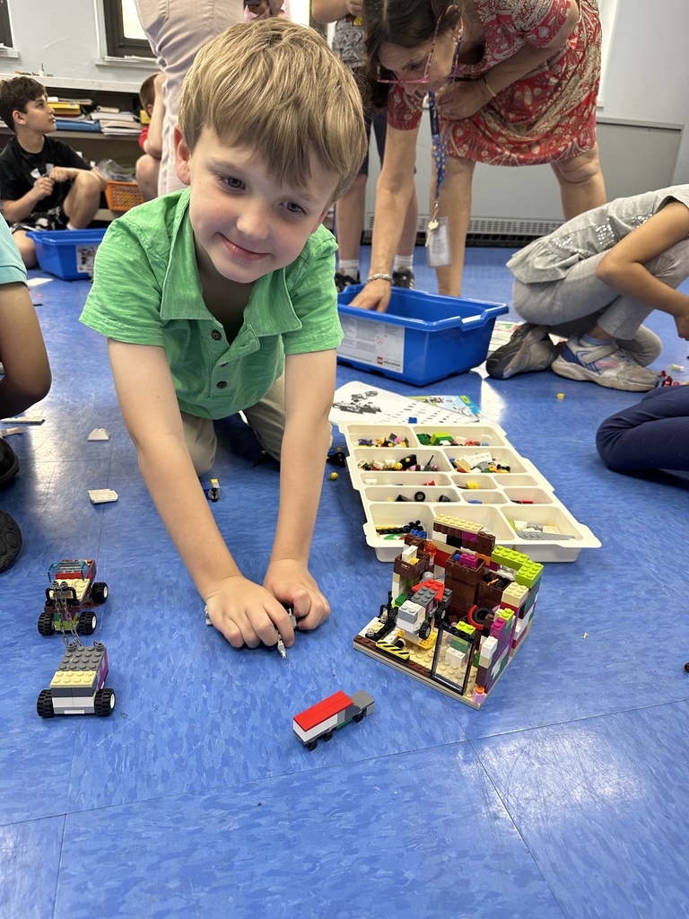 A student working on a lego creation, on the floor