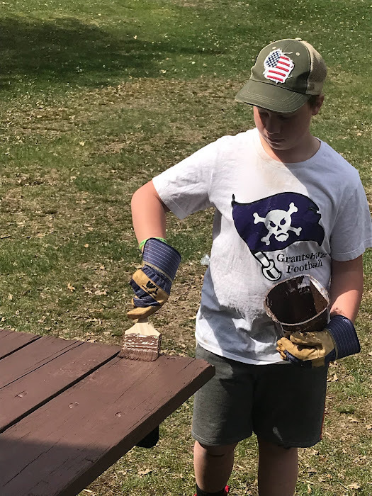 Indvidual student staining a picnic table.