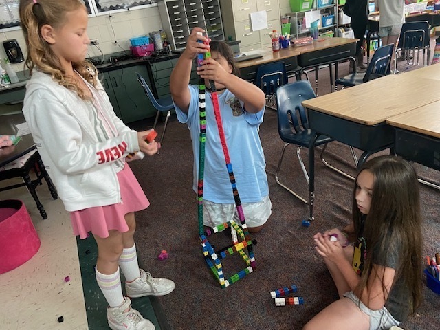 three girls building a structure out of cubes
