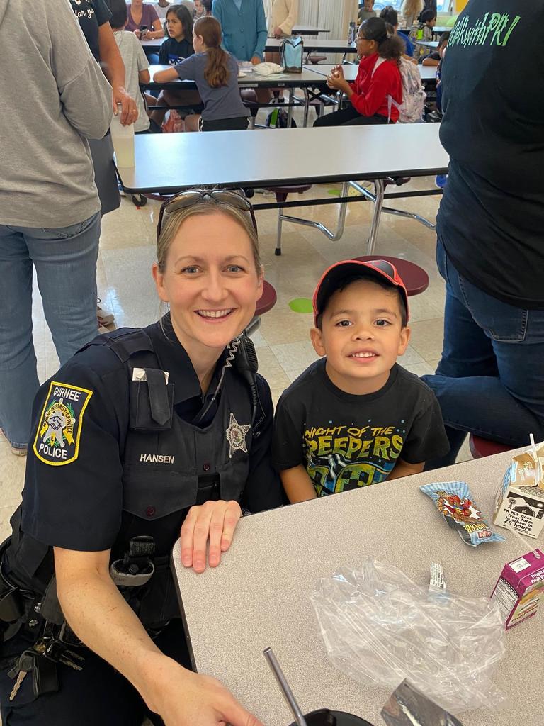 police officer poses for a photo with a young student