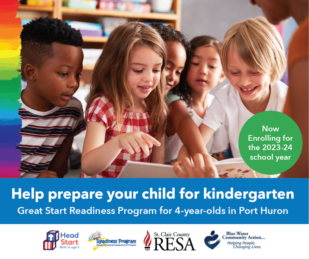 Children reading with a teacher and pointing towards a book