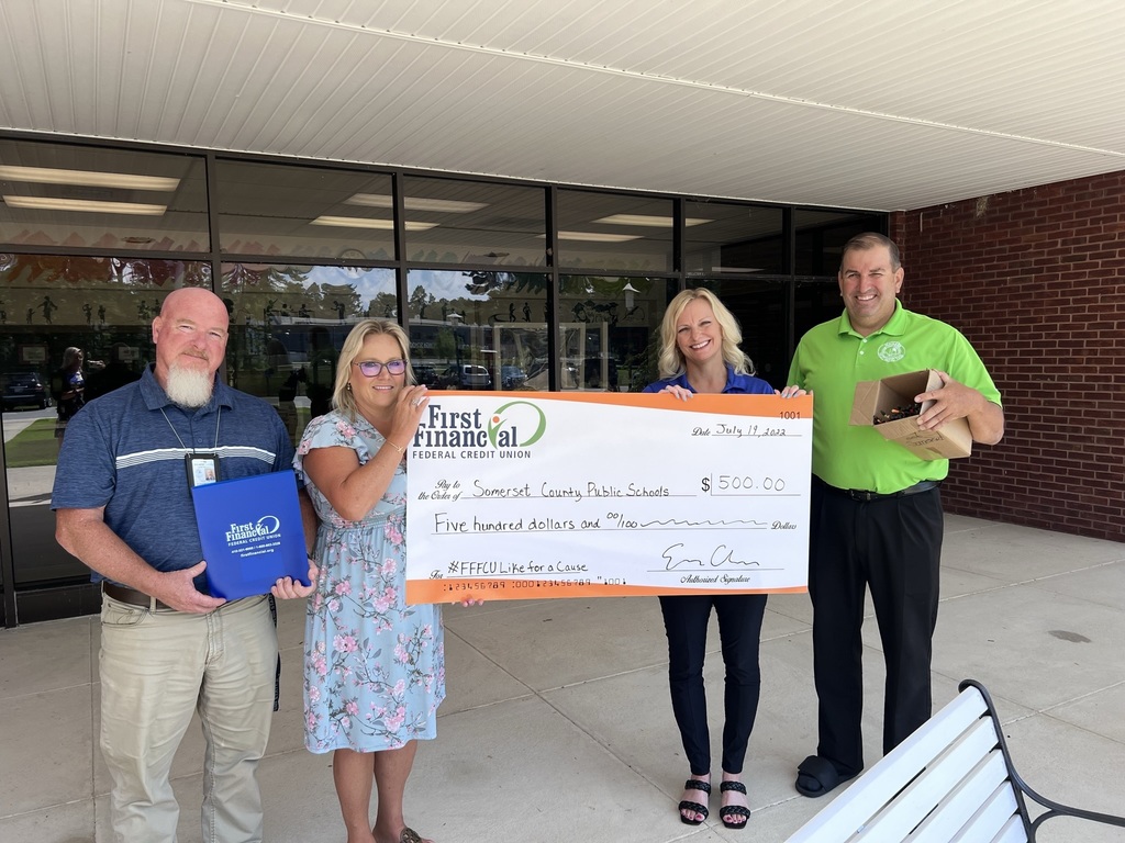 two men and two women standing outside holding a big check for $500 from FFFCU