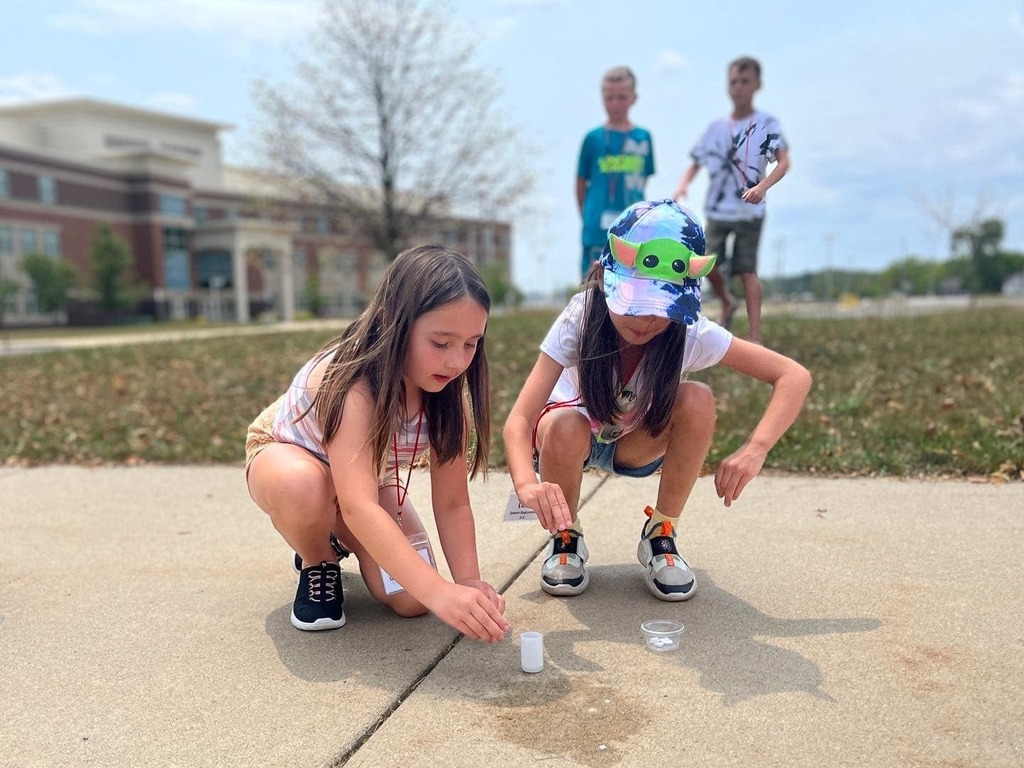 Two girls drop tablets into a canister