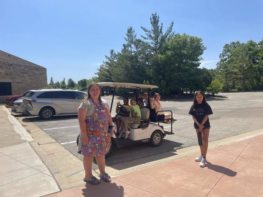 Students outside on the golf cart and standing by on Earth Field Day.