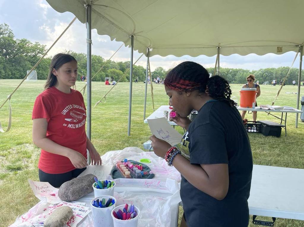 Two students blowing bubbles on their artwork for Mother Earth.