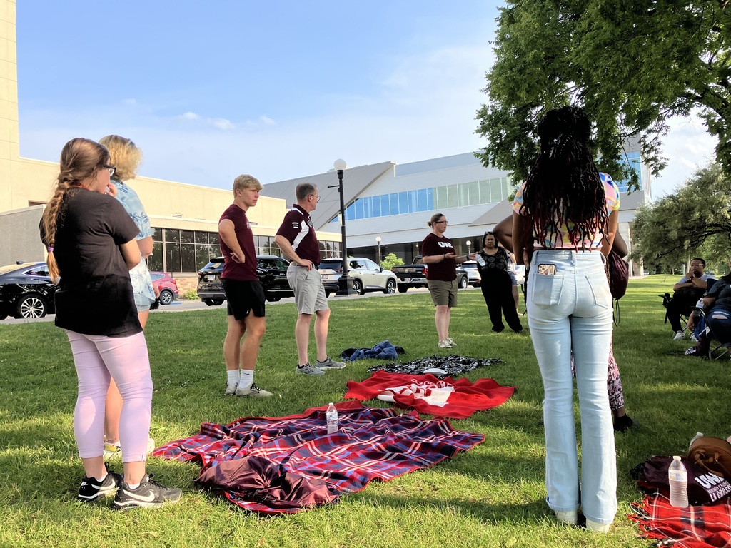 Several students and counselors talking outside with blankets on the lawn.