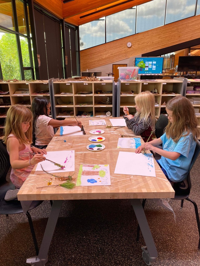 Four students painting on a table.