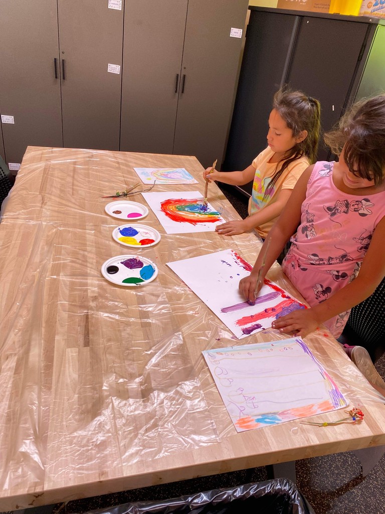 Two students painting on a table.