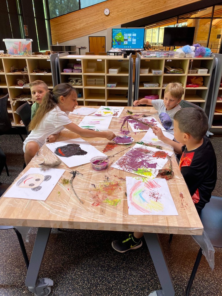 Four students painting on a table.