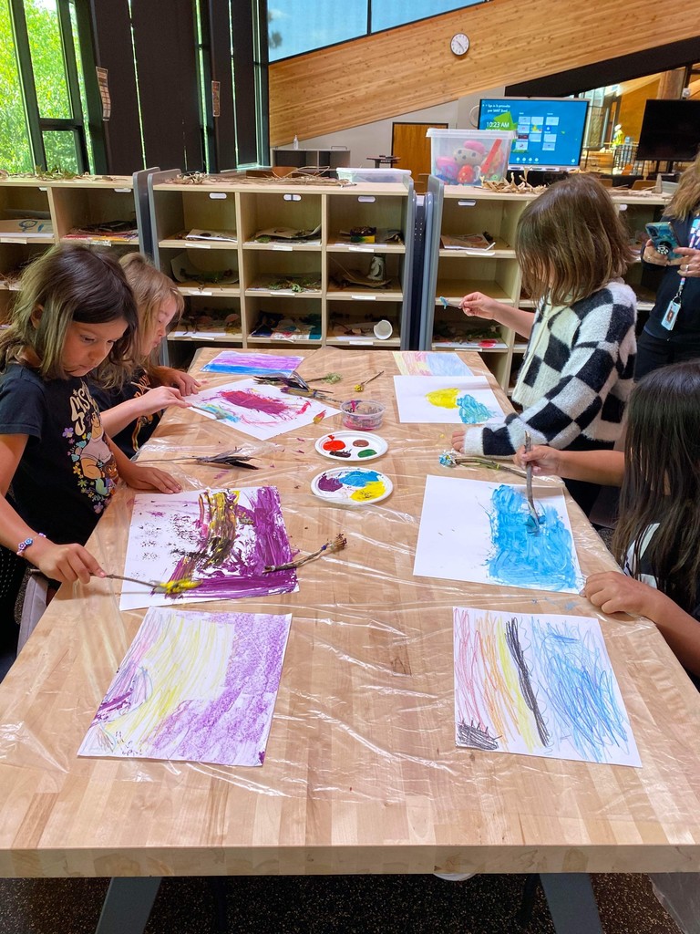 Four students painting on a table.