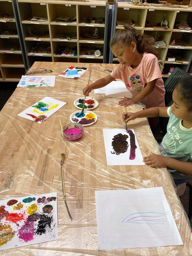 Two students painting on a table.