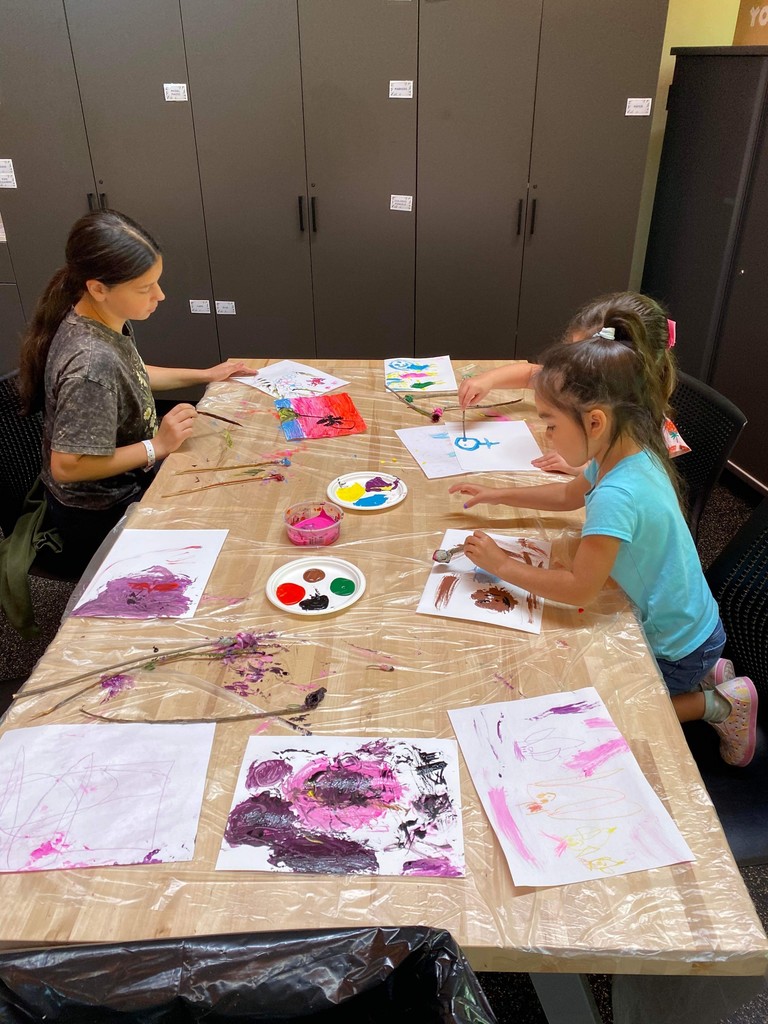 Three students painting on a table.