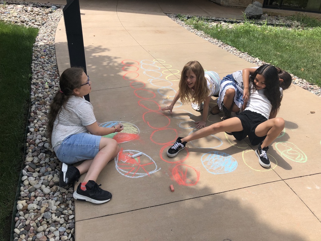 Four students playing twister with sidewalk chalk.