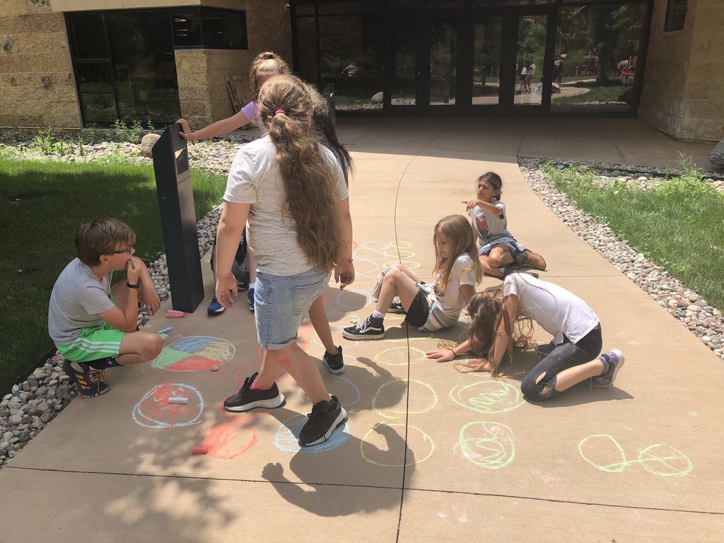 Seven students playing games with sidewalk chalk.