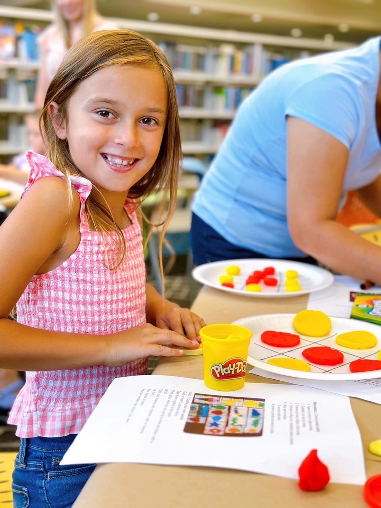 A young girl plays with play-doh at the libary