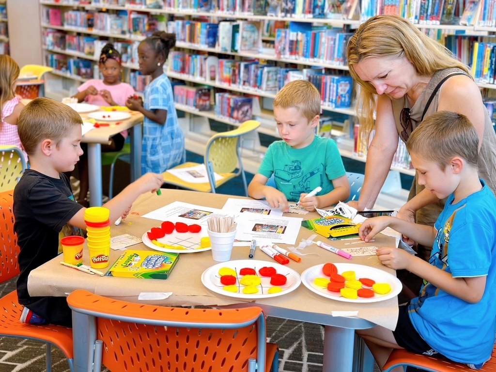 Three students and an adult doing a craft at the library.