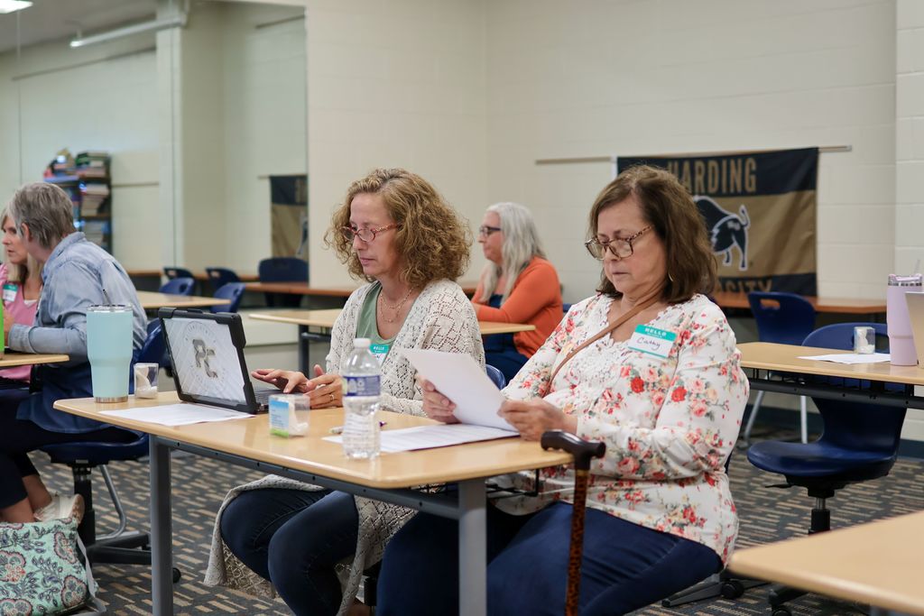 two women work at a desk in a classroom