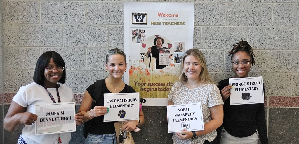New teachers holding up a sign as to which school they are representing