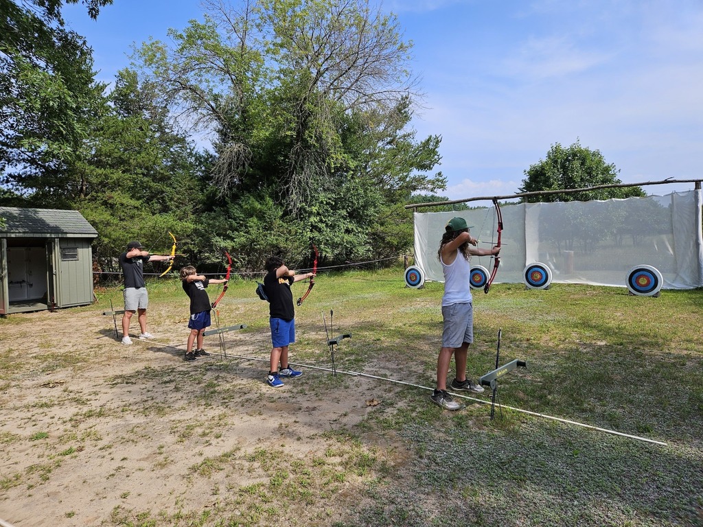 Four family members doing archery outside.