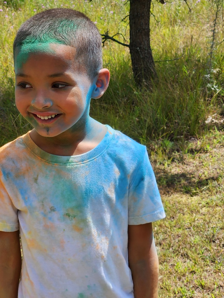 Little boy smiling with color powder on him.