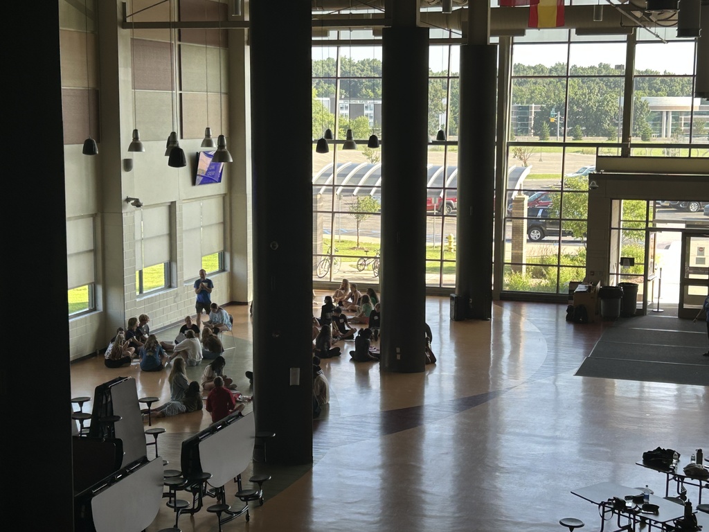 large room with students sitting on the floor working in groups