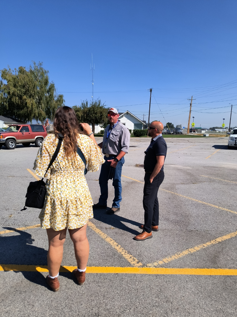 Three people talking in parking lot.