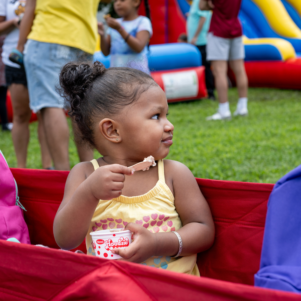 A young girl with ice cream smiling as she looks at her surrounding. 