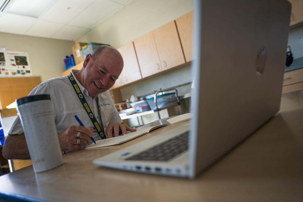 male teacher scribbling with a laptop in the foreground