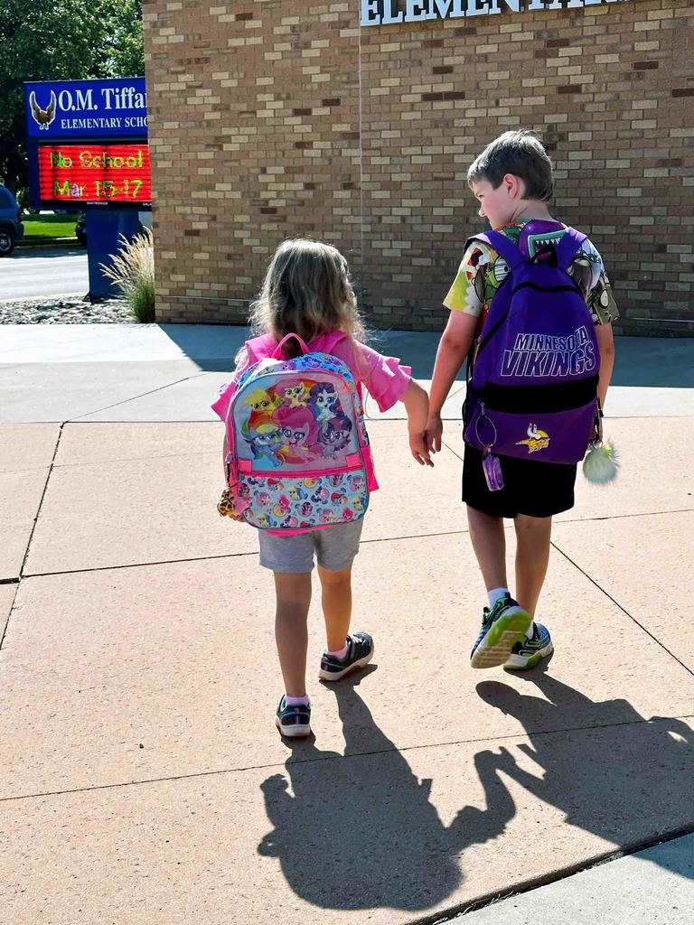 Siblings holding hands walking toward O.M. Tiffany