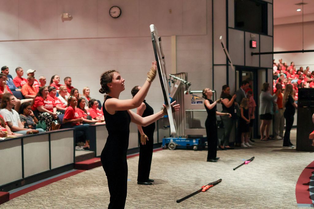 color guard members twirl batons in an auditorium