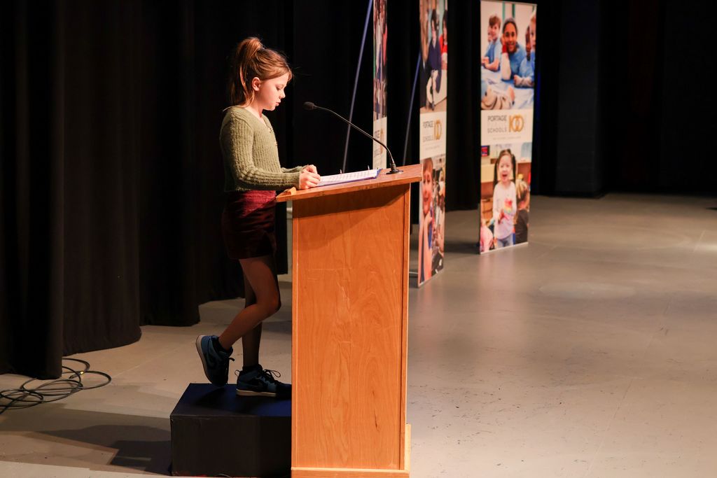 a young girl speaks at a podium in an auditorium
