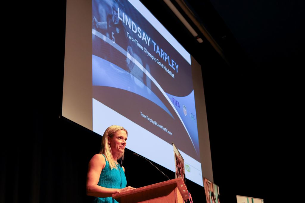 A woman speaks at a podium in an auditorium