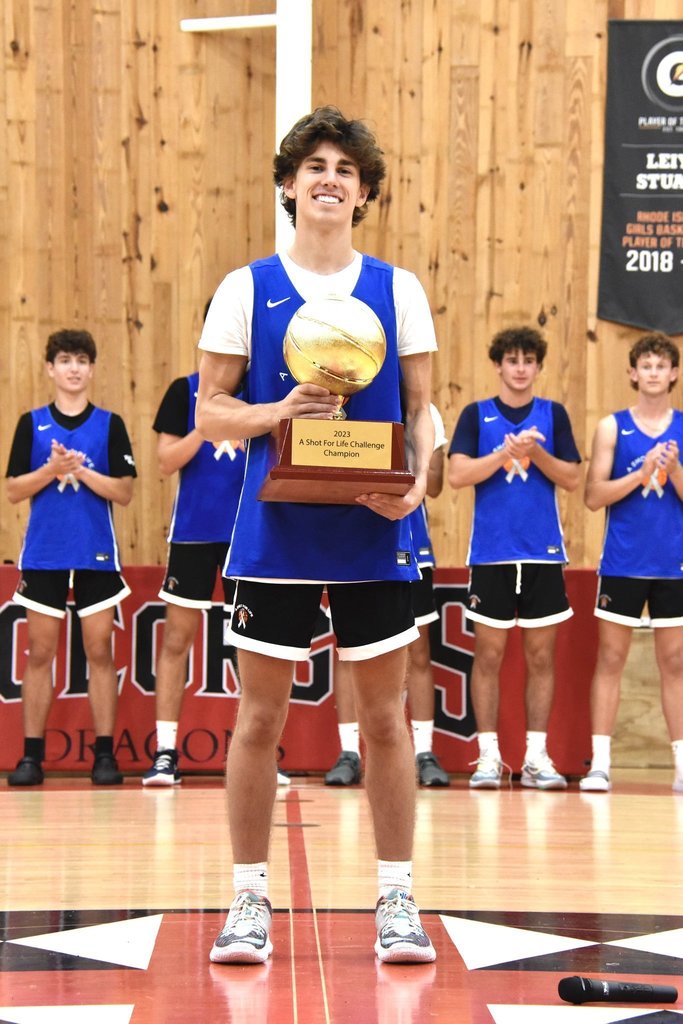 student poses with basketball trophy