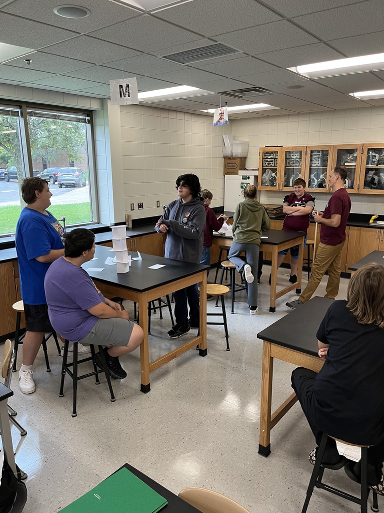 students standing near tables building towers