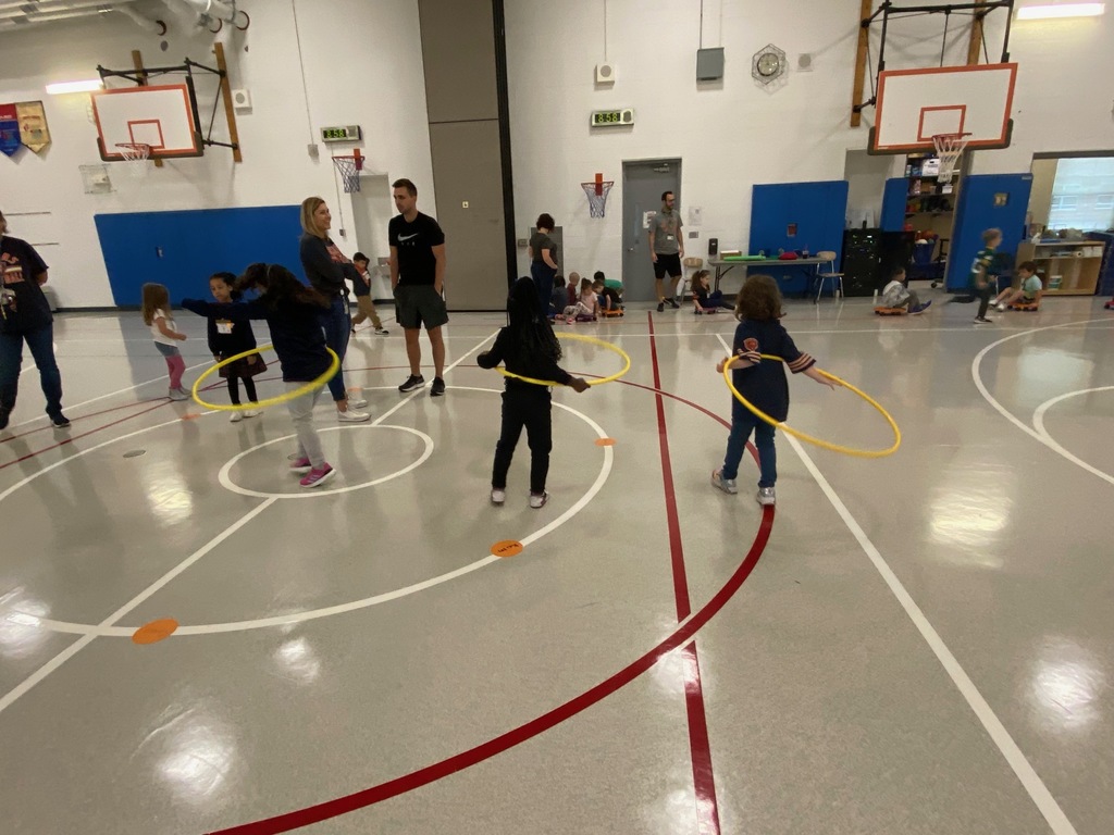 three students hula hoop in the gym