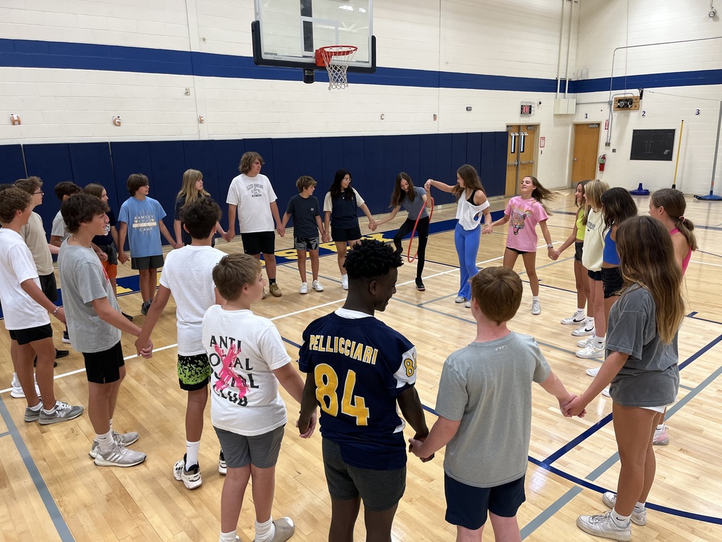 8th grade students participating in a team building game- students have to pass a hula hoop between one another without letting go of hands