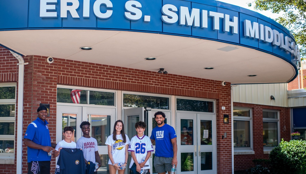 Giants with students in front of school