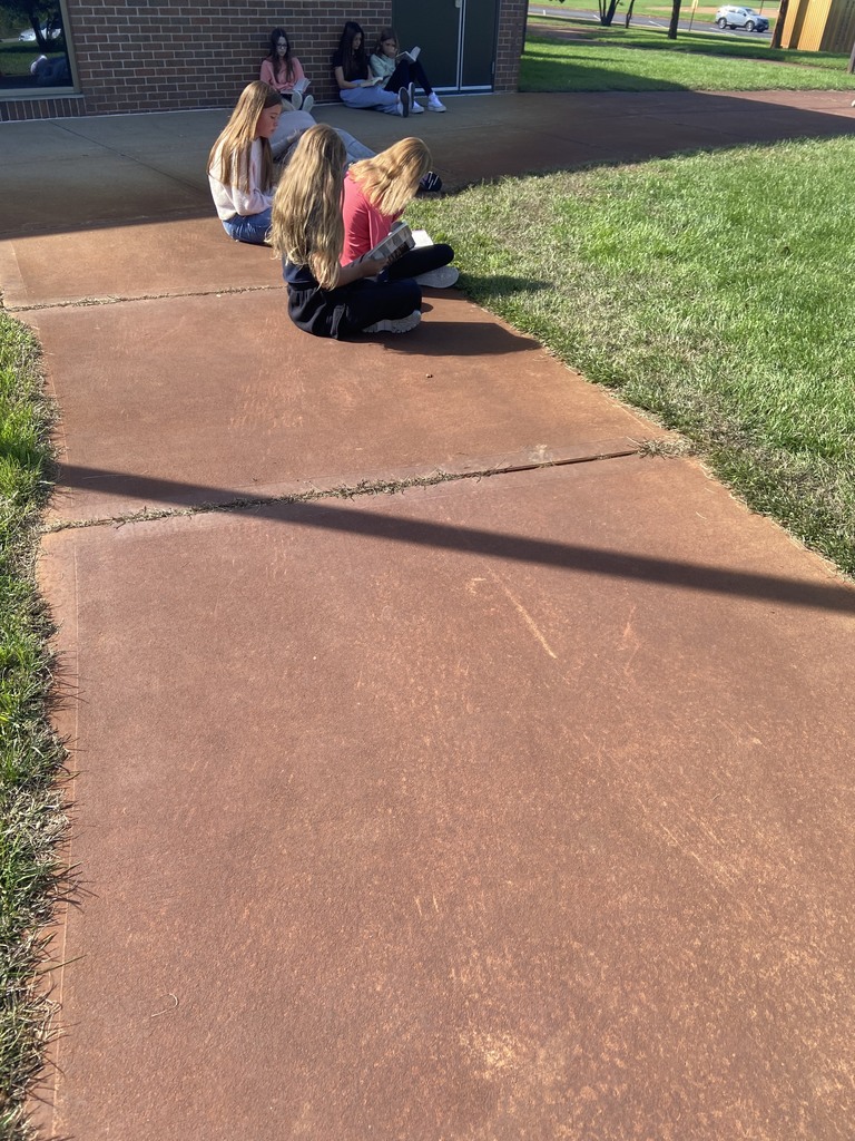 6 students sitting and reading outside