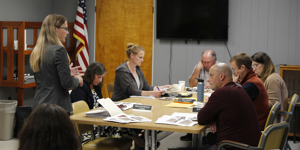 Superintendent speaking to members of village board sitting at table
