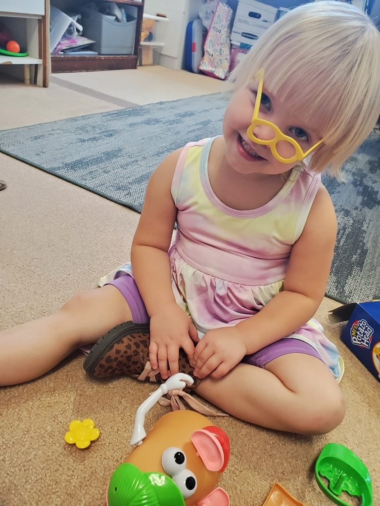 Student sitting on the floor with small plastic glasses on her face