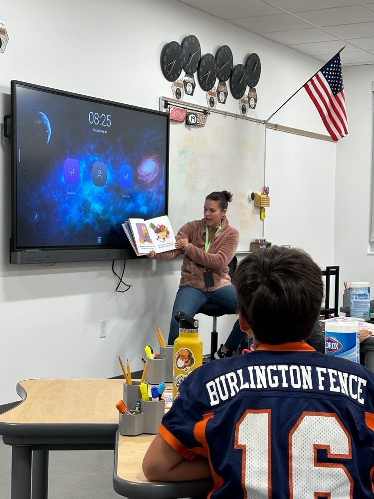 a woman reads aloud to a class 