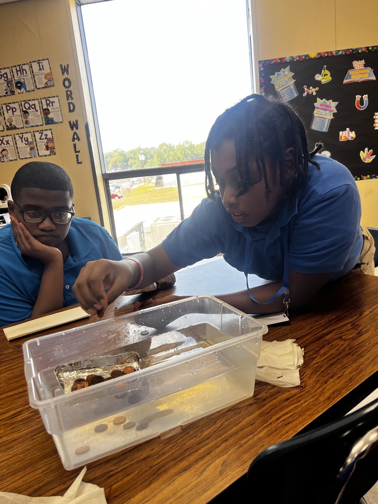 A student puts pennies on a tin raft.