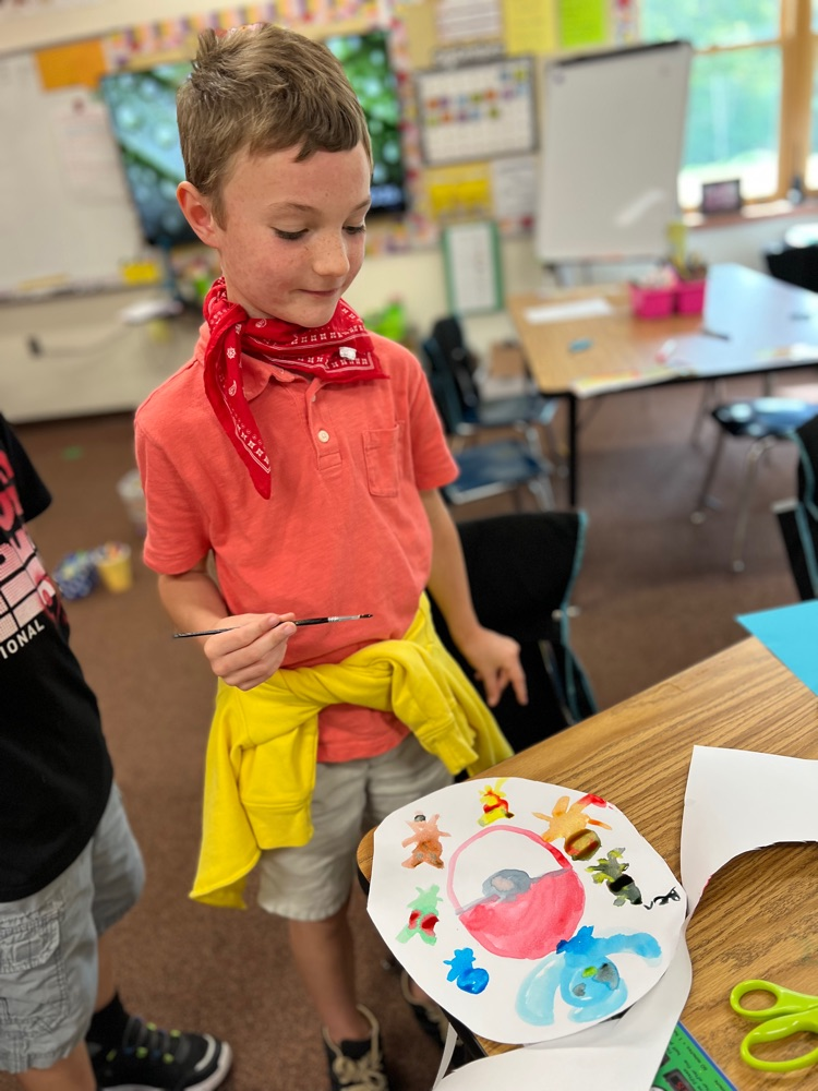 student looking down at his dot artwork