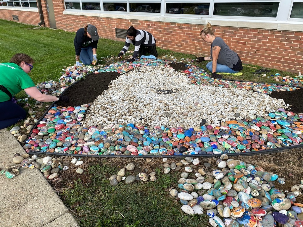 Volunteers add painted rocks to the rock garden