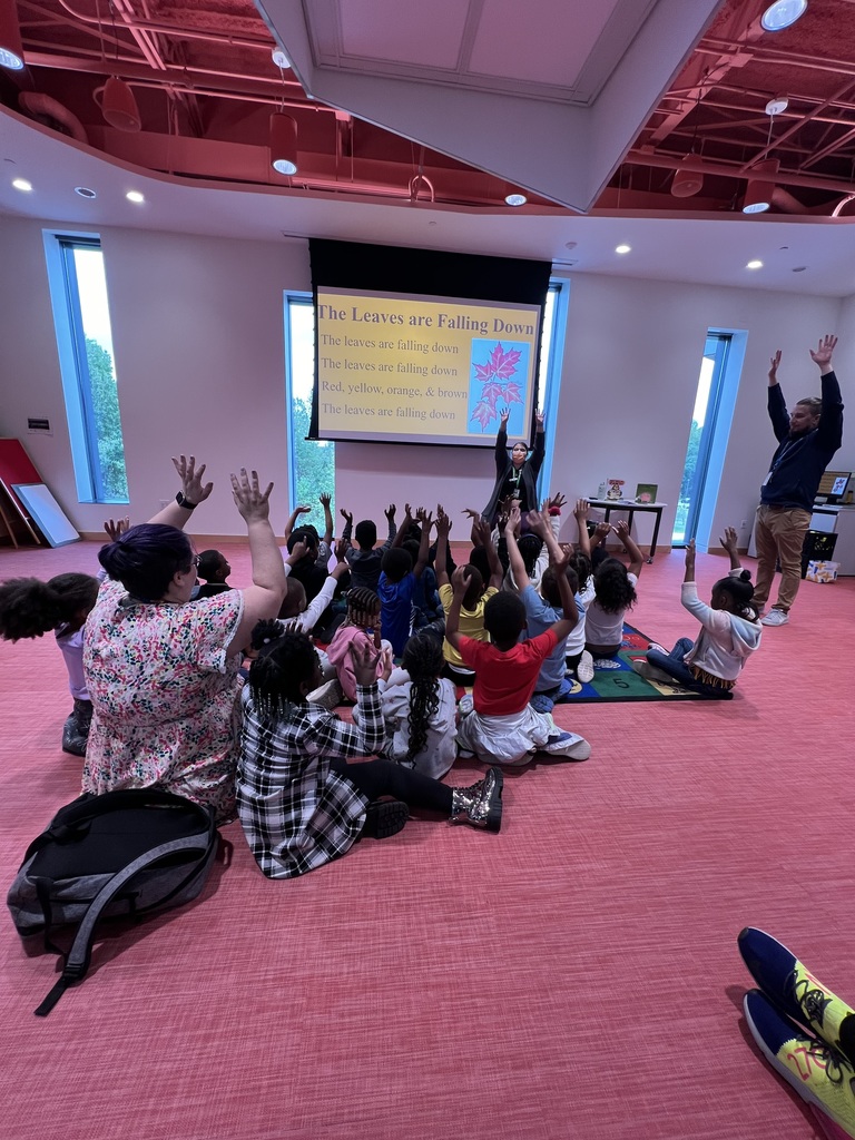 A class sits on the ground with arms raised to the sky.