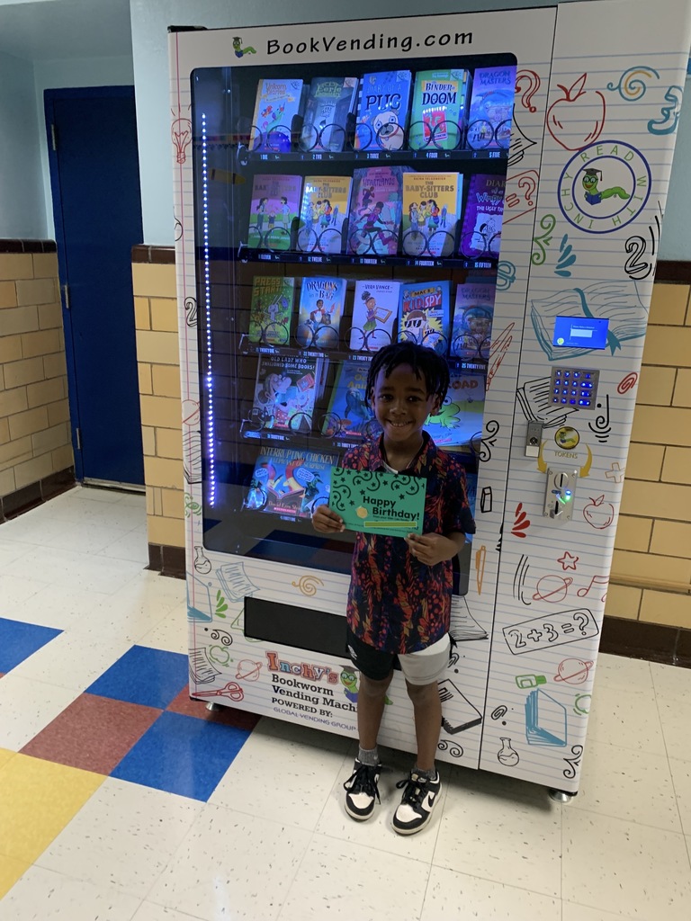 A student stands with his birthday certificate and coin.