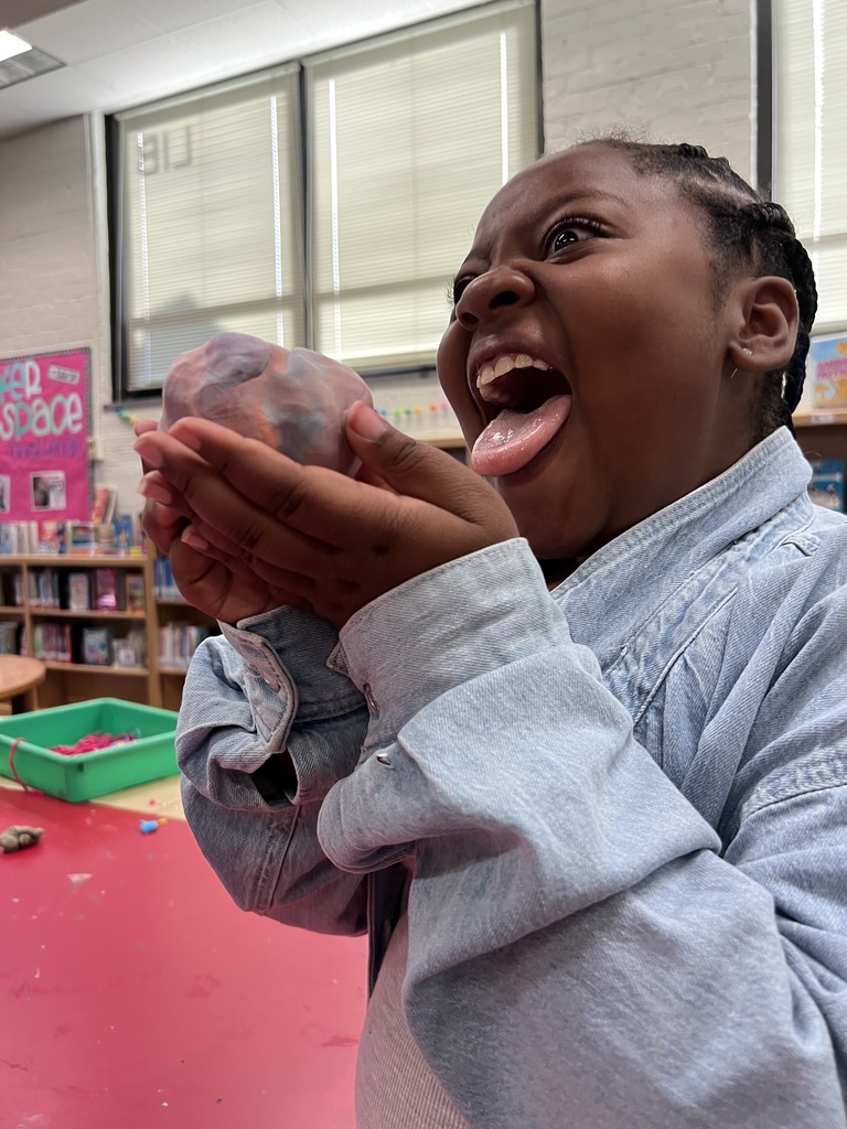 A student pretends to eat a ball of "ice cream" (Play-Doh).
